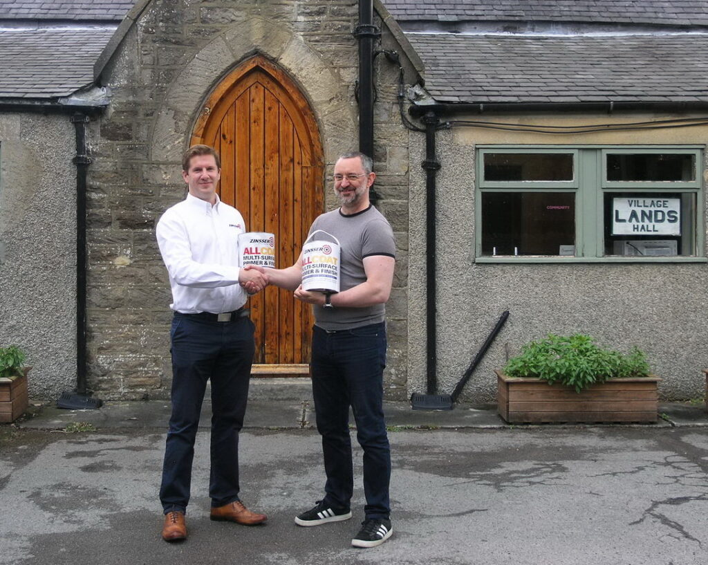 Philip Mobley presents Zinsser AllCoat paint to Glenn Reffin at Lands Village hall.